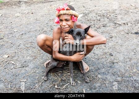 Wamena, Indonésie - 9 janvier 2010 : homme de la tribu Dani assis avec son chien, Dugum Dani Village, Nouvelle-Guinée indonésienne Banque D'Images