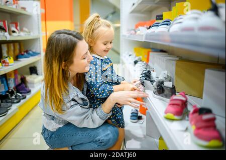 La mère et le bébé recherchent des chaussures dans le magasin pour enfants Banque D'Images