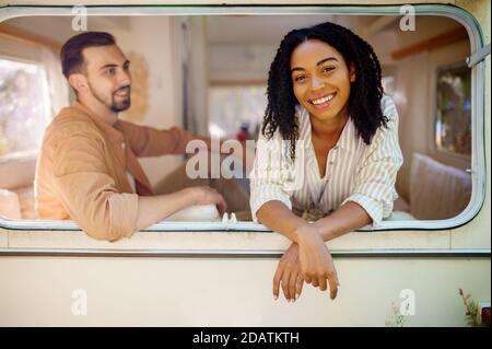 Le couple regarde par la fenêtre du véhicule de camping, campant dans la remorque Banque D'Images