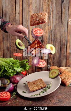 Viande grillée avec des tranches d'oignon, d'avocat et de tomate volantes. Porc grillé avec côte sur une fourchette. Banque D'Images