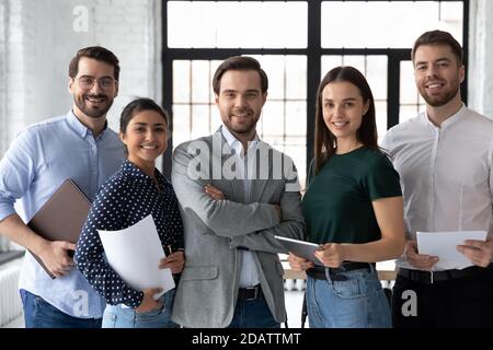 Un chef d'équipe homme confiant se pose pour un portrait avec des employés divers Banque D'Images