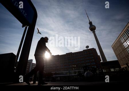 15 novembre 2020, Berlin: Un homme avec un gardien de la bouche et du nez traverse Alexanderplatz en face de la tour de télévision. Photo: Christoph Soeder/dpa Banque D'Images