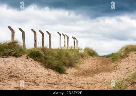 Les dunes de sable et les poteaux de clôture en angle avec un moody sky à une plage à Hartlepool en Angleterre du Nord-Est Banque D'Images