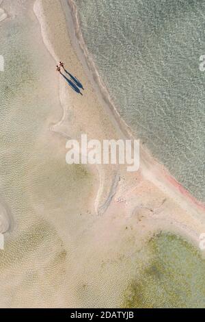 Vue aérienne des personnes marchant et jetant de longues ombres sur le bar de sable de la plage d'Elafonisi, l'une des destinations touristiques les plus populaires dans les sud du pays Banque D'Images