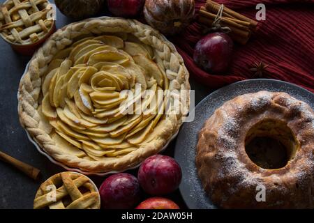 Tartes aux pommes de différents types sur une table avec des fruits frais, des bâtonnets de cannelle et des citrouilles. Idées de menu d'automne. Dessert maison photo en gros plan. Banque D'Images