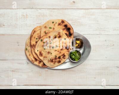Pain naan frais sur fond de bois blanc avec espace de copie. Vue de dessus de plusieurs pains plats naan parfaits sur plateau métallique Banque D'Images
