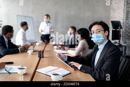Homme d'affaires asiatique Entrepreneur en masque de visage assis dans le bureau moderne Banque D'Images