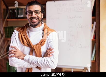 Homme enseignant indien souriant posé près de Blackboard debout à la maison Banque D'Images