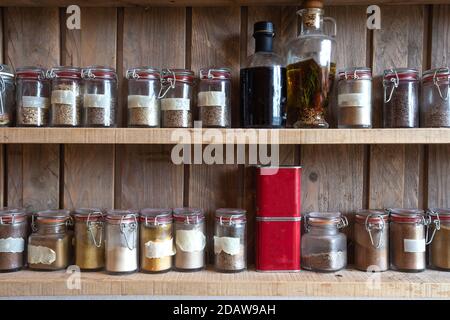 Bouteilles avec épices et assaisonnements dans un rack en bois. Différentes herbes biologiques pour dans la cuisine look vintage Banque D'Images