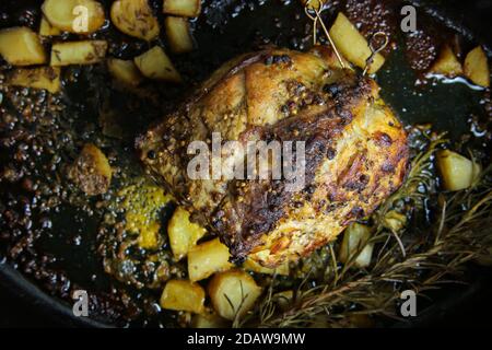 Gros plan sur la viande de longe de porc allemande fraîche rôtie en cocotte avec croûte de poivre, brindilles de romarin et oignons (priorité au rôti) Banque D'Images