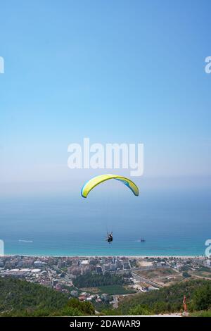 Le parapente orange survole une vallée de montagne par une belle journée d'été. Parapente dans les montagnes dans le ciel Banque D'Images