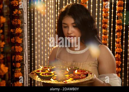 Portrait d'une femme indienne tenant des diyas et des lampes à l'occasion des fêtes de Diwali. Fêtes à la maison Banque D'Images