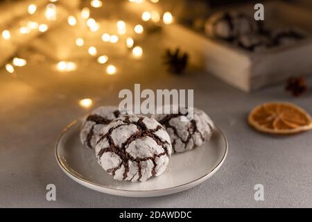 petits gâteaux au chocolat faits maison dans une assiette blanche contre les lumières de noël floues. Banque D'Images