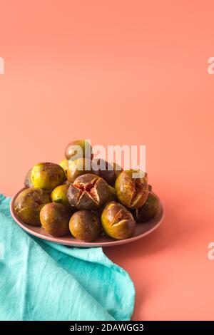 Beaucoup de figues sont sur une plaque rose à côté d'une plaque de lin turquoise. Verticale. Copier l'espace Banque D'Images