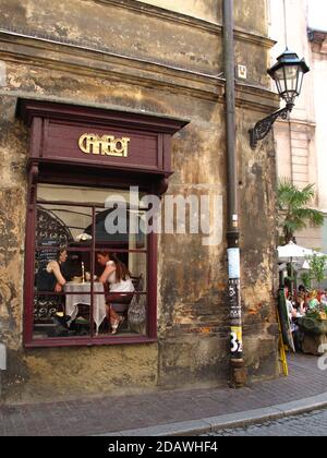 Clients de Lady dans une table de fenêtre photographiée de l'extérieur au café Camelot, un café-restaurant renommé de Cracovie dans la vieille ville. Banque D'Images