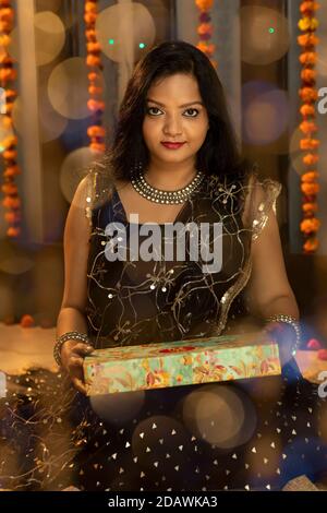 Une femme indienne heureuse tenant un cadeau à l'occasion du festival de Diwali, connu sous le nom de Festival des lumières. Banque D'Images