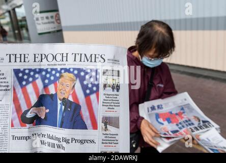 Une femme distribue les journaux en chinois et en anglais qui présente sur sa couverture l'actuel président américain Donald J. Trump à Hong Kong. Banque D'Images