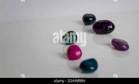 pierres précieuses de couleur éparpillées sur un fond blanc uni réfléchissant. Cristaux clairs simples multicolores Banque D'Images