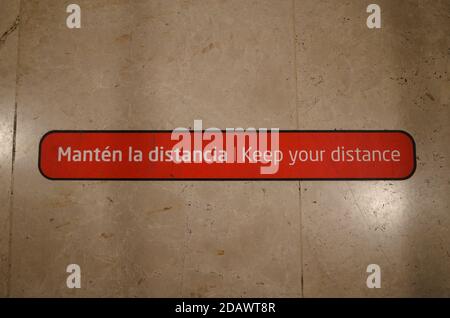 Lors d'une pandémie, conservez votre message d'avertissement de distance sur le sol de l'aéroport international en espagnol et en anglais. Banque D'Images