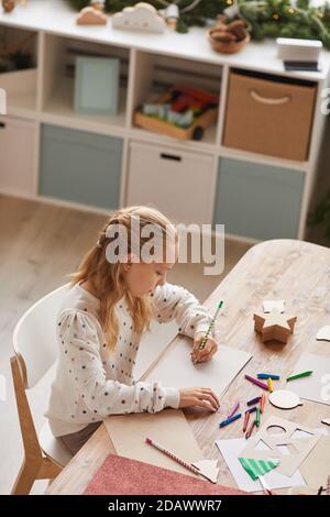 Portrait vertical à grand angle d'une adolescente blonde qui fait ses devoirs tout en étant assis au bureau à l'intérieur de la maison, espace de copie Banque D'Images