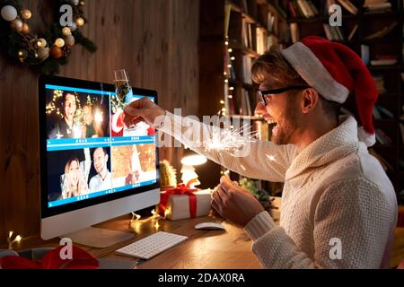 Un jeune homme porte un chapeau de Noël célèbre la bonne année par appel vidéo. Banque D'Images