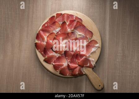 Speck, jambon fumé typique du Tyrol du Sud, Alto Adige en Italie - tranches sur planche à découper en bois dans la vue de dessus Banque D'Images