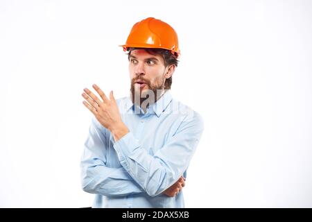 Un homme dans une industrie de construction de chemise de casque orange a travaillé arrière-plan clair Banque D'Images