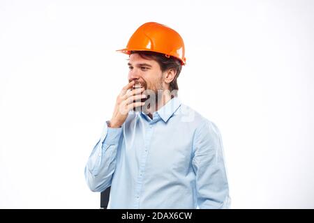 Un homme dans une industrie de construction de chemise de casque orange a travaillé arrière-plan clair Banque D'Images