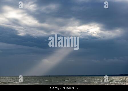 Southampton, Royaume-Uni, 15 novembre 2020. Un faisceau de lumière du soleil traverse les nuages orageux au-dessus du Solent, projetant un grand rayon de lumière concentré sur le plan d'eau qui sépare le continent britannique de l'île de Wight. Banque D'Images