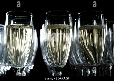 Des verres de vin mousseux se tiennent sur un gros plan sur fond noir Banque D'Images