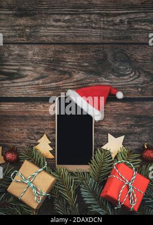 Fond de concept de Noël.smartphone avec chapeau de père noël et arbre de Noël branches sur table en bois Banque D'Images