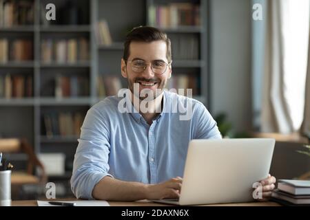 Employé de bureau assis au bureau souriant en regardant l'appareil photo Banque D'Images
