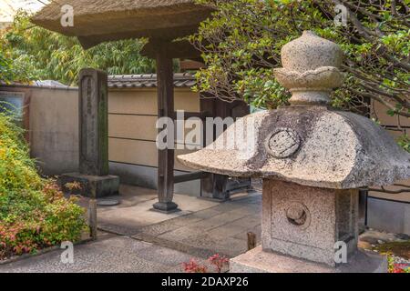 tokyo, japon - novembre 05 2020 : lanterne en pierre japonaise sur le côté de la porte principale de Tamonji-Sanmon avec un toit de chaume dans le temple bouddhiste de Tamonji Banque D'Images