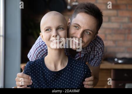 Un mari optimiste et affectueux qui se serre les épaules d'une femme du millénaire atteinte d'un cancer Banque D'Images