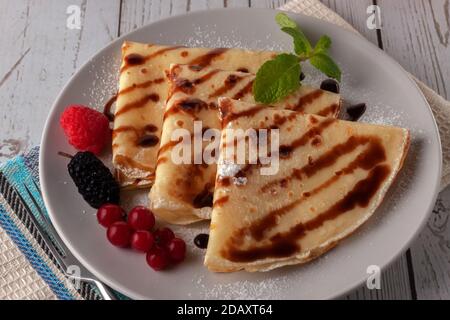 Crêpes aux framboises, aux raisins de Corinthe et au chocolat, décorées d'une feuille de menthe Banque D'Images