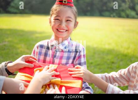 Bonne petite fille dans le chapeau rouge de Santa et tenue de Noël présente Banque D'Images