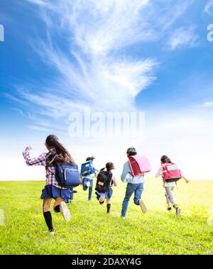 vue arrière des enfants de l'école primaire qui s'amusent sur l'herbe Banque D'Images