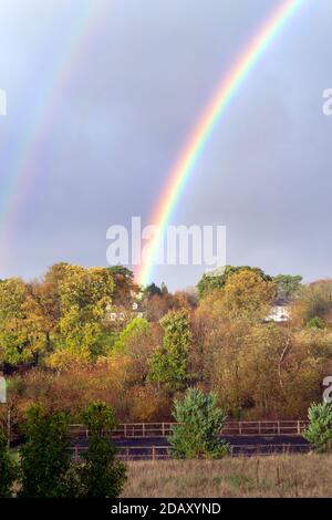 Double arc-en-ciel brillant sur les arbres avec des couleurs d'automne Banque D'Images