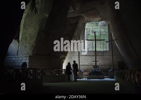 Visiteurs photographiés devant les trois croix à l'intérieur du cimetière Fontanelle (Cimitero delle Fontanelle) à Naples, Campanie, Italie. L'ancienne maison de charnel (ossuary) située dans une grotte dans le district de Materdei était l'endroit où le culte spontané de la dévotion aux restes de morts sans nom s'est développé à Naples. Les défenseurs du culte ont payé des visites aux crânes sans nom dans l'ossuaire pour les adopter et même donner les noms des crânes. Les crânes adoptés ont été placés à l'intérieur de la boîte décorée et sont devenus l'objet de prières régulières et d'offrande votive. Banque D'Images