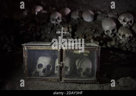 Trois crânes humains en boîte au cimetière Fontanelle (Cimitero delle Fontanelle) à Naples, Campanie, Italie. L'ancienne maison de charnel (ossuary) située dans une grotte dans le district de Materdei était l'endroit où le culte spontané de la dévotion aux restes de morts sans nom s'est développé à Naples. Les défenseurs du culte ont payé des visites aux crânes sans nom dans l'ossuaire pour les adopter et même donner les noms des crânes. Les crânes adoptés ont été placés à l'intérieur de la boîte décorée et sont devenus l'objet de prières régulières et d'offrande votive. Banque D'Images