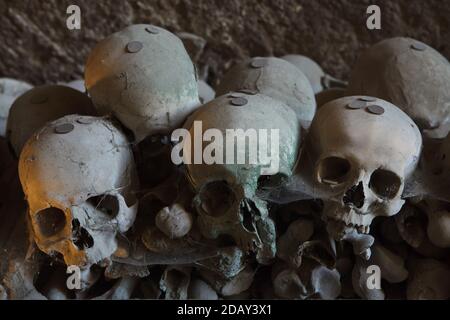 Crânes et os humains empilés au cimetière Fontanelle (Cimitero delle Fontanelle) de Naples, Campanie, Italie. L'ancienne maison de charnel (ossuary) située dans une grotte dans le district de Materdei était l'endroit où le culte spontané de la dévotion aux restes de morts sans nom s'est développé à Naples. Les défenseurs du culte ont payé des visites aux crânes sans nom dans l'ossuaire pour les adopter et même donner les noms des crânes. Les crânes adoptés ont été placés à l'intérieur de la boîte décorée et sont devenus l'objet de prières régulières et d'offrande votive. Banque D'Images