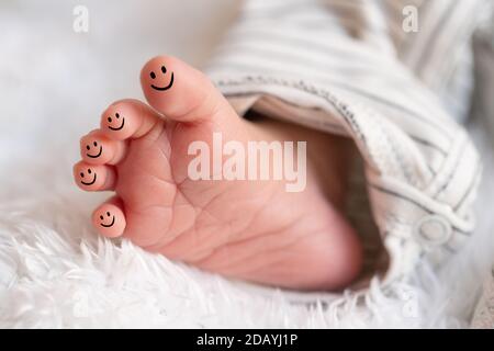 petits pieds de bébé nouveau-né avec émoticônes smiley dessinées sur eux Banque D'Images