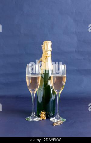 Bouteille de champagne de la Saint-Sylvestre et verres avec ornements dorés et décorations sur fond bleu Banque D'Images