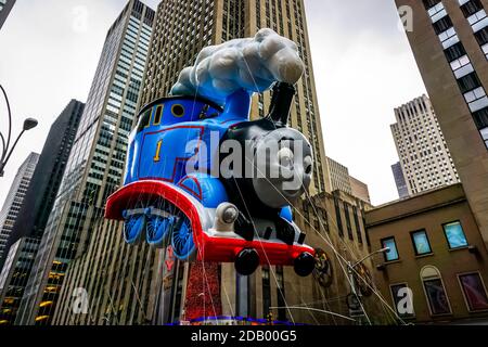 Thomas le Tank Engine flotte dans les airs pendant la parade de Thanksgiving de Macy le long de l'avenue des Amériques avec la radio Music Hall en arrière-plan. Banque D'Images