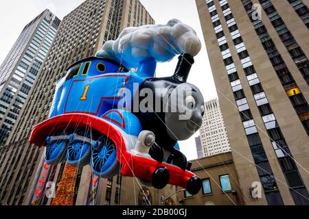 Thomas le Tank Engine flotte dans les airs pendant la parade de Thanksgiving de Macy le long de l'avenue des Amériques avec la radio Music Hall en arrière-plan. Banque D'Images