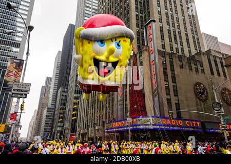 Le ballon SpongeBob Squarepaants flotte dans l'air pendant l'action de grâce de Macy Parade de jour le long de l'avenue des Amériques avec radio Music Hall en arrière-plan Banque D'Images