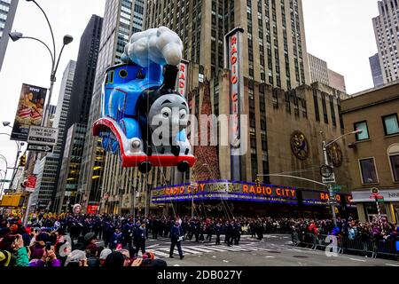 Thomas le Tank Engine flotte dans les airs pendant la parade de Thanksgiving de Macy le long de l'avenue des Amériques avec la radio Music Hall en arrière-plan. Banque D'Images