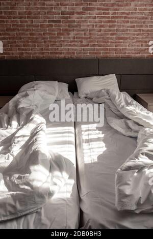 Chambre style loft, lits non faits avec couvertures Banque D'Images