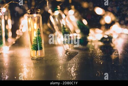 noël encore la vie avec de petits arbres de noël dans des pots en verre et des lumières de noël brillantes Banque D'Images