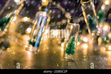 sapin de noël enneigé dans un pot en verre. éclairage décoratif de noël sur fond brillant Banque D'Images